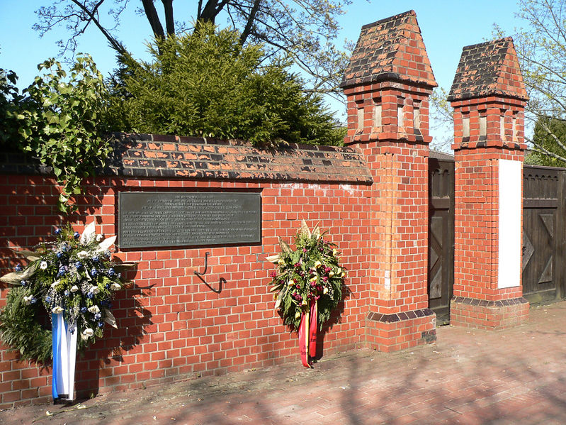 Mahnmal mit Inschrift und Kränzen am alten Eingangstor neben dem ehemaligen Direktorenhaus